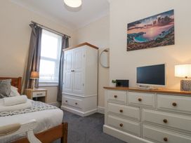 A bedroom with a bed side table lamp wardrobe and dresser with a monitor and a landscape picture on the wall at Royal Victoria House in Scarborough