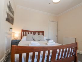 A bedroom with a wooden bed frame white bedding pillows folded towels bedside tables lamp and a painting on the wall at Royal Victoria House in Scarborough