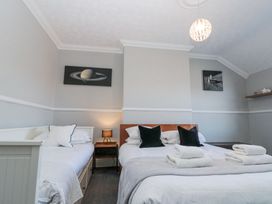 A bedroom with two beds a nightstand with a lamp and space-themed wall art at Royal Victoria House in Scarborough