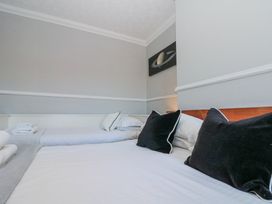 A bedroom with two beds white sheets black pillows and a painting of Saturn on the wall at Royal Victoria House in Scarborough