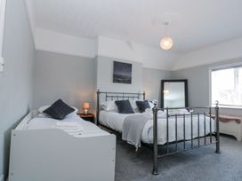 A bedroom with a double bed and a single bed a bedside table with lamp a large mirror and a window at Royal Victoria House in Scarborough
