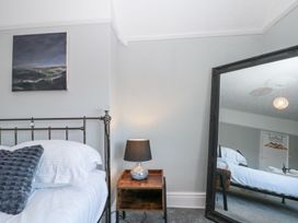 A bedroom corner with a bed a wooden bedside table with a lamp and a large mirror at Royal Victoria House in Scarborough