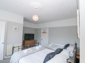 A bedroom with two beds a wooden dresser with a television and a hanging light at Royal Victoria House in Scarborough