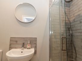 A bathroom with a round mirror a sink with liquid soap and a glass shower enclosure at Royal Victoria House in Scarborough