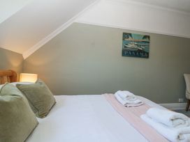 A bedroom with a bed made with white sheets and green pillows beside a wall with a Panama poster at Royal Victoria House in Scarborough