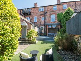 A backyard with a brick house patio seating and greenery at Royal Victoria House in Scarborough