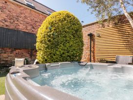 An outdoor hot tub with bubbling water near a bush and patio chairs at Royal Victoria House in Scarborough