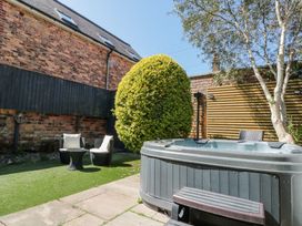 A backyard with a hot tub two chairs a small table a round bush and an olive tree at Royal Victoria House in Scarborough