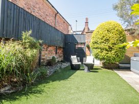 A garden area with two chairs and a table on artificial grass next to a large round bush and wooden fences at Royal Victoria House in Scarborough