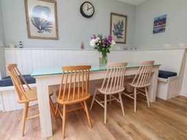 A dining room with a table, chairs, vase, and wall art at 21 Eskdaleside, Sleights