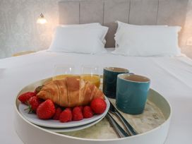 A breakfast tray with fruit and drinks on a bed at 21 Eskdaleside in Sleights