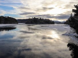 A landscape featuring water, trees, and mountains at Wildcat Lodge in Feshiebridge near Aviemore