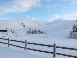 A snow-covered landscape with mountains and a fence at Golden Eagle Lodge in Aviemore