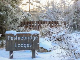 A sign for Feshiebridge Lodges surrounded by snow at Red Deer Lodge Feshiebridge near Aviemore