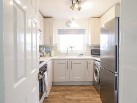 A kitchen with cabinets, oven, sink, refrigerator and washing machine at 8 Glan Ysgethin in Barmouth