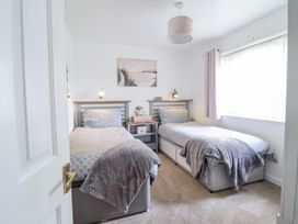 A bedroom with two beds and a bedside table at 8 Glan Ysgethin in Barmouth