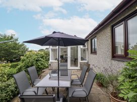 A garden with a table and chairs under an umbrella at 8 Glan Ysgethin in Barmouth