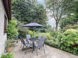 A garden with a table and chairs under an umbrella at 8 Glan Ysgethin in Barmouth