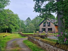 A house with a pathway and trees in the garden at Romsey Lodge in Wark