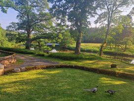 A garden with trees and a river at Romsey Lodge in Wark