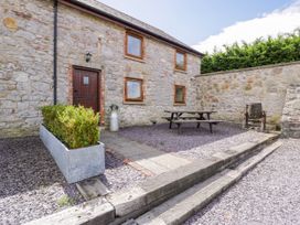 An outdoor area with a stone building, table, and seating at Stabal-y-Gwedd in Dolwen near Abergele