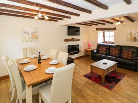 A living room and dining area with furniture and a television at Stabal-y-Gwedd in Dolwen near Abergele