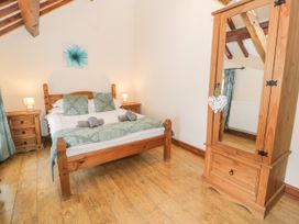 A bedroom with a bed and wooden furniture at Stabal-y-Gwedd in Dolwen near Abergele