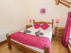A bedroom with a wooden bed and pink decor at Stabal-y-Gwedd in Dolwen near Abergele