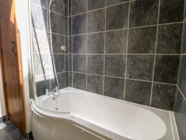 A bathtub with shower in a bathroom at Stabal-y-Gwedd in Dolwen near Abergele