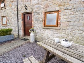 An outdoor area with a table, tea pot, and flower pot at Stabal-y-Gwedd in Dolwen near Abergele
