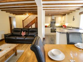 A living room with a sofa and kitchen area at Beudy Bach in Dolwen near Abergele