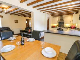 A dining room with a table and kitchen in Beudy Bach Dolwen near Abergele