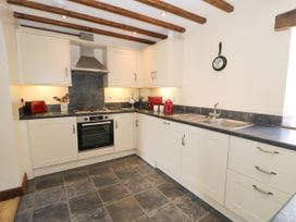 A kitchen with cabinets, a sink, and appliances at Beudy Bach Dolwen near Abergele
