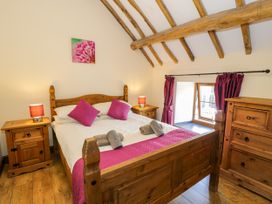 A bedroom with a wooden bed and furniture at Beudy Bach Dolwen near Abergele