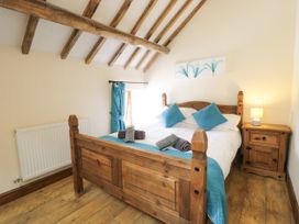 A bedroom with a wooden bed and bedside table at Beudy Bach Dolwen near Abergele