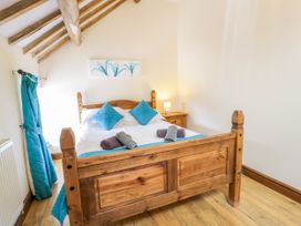 A bedroom with a wooden bed and decorative pillows at Beudy Bach in Dolwen near Abergele