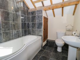 A bathroom with a bath tub, toilet, and sink at Beudy Bach in Dolwen near Abergele