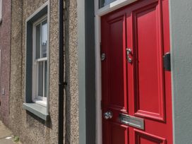 A red door with a handle and letterbox next to a window at Number Thirty-Nine in Ulverston