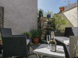 A wine bottle and glasses on a table with chairs in an outdoor space at Number Thirty-Nine Ulverston