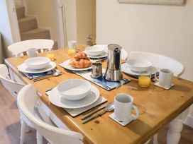 A dining table set with mugs and croissants at Cobbler's Cottage Mundesley