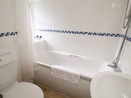 A bathroom with a bathtub and a toilet at Cobbler's Cottage Mundesley