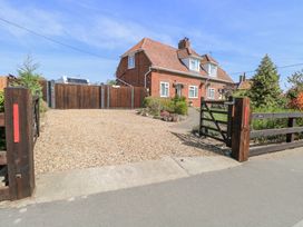 A brick house with a tiled roof behind wooden gates and a gravel driveway at Lillies Pad in Methwold near Feltwell
