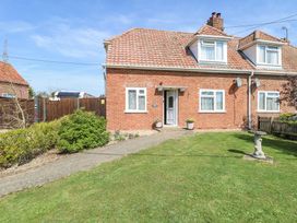 A brick house with a tiled roof and front garden with grass and bushes at Lillies Pad in Methwold near Feltwell