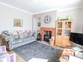 A living room with a patterned sofa a wood burning stove a wooden cabinet and a television at Lillies Pad in Methwold near Feltwell