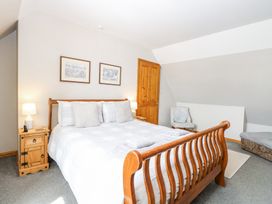 A bedroom with a wooden bed and white bedding two bedside tables with lamps a chair with a cushion and a wooden door at Lillies Pad in Methwold near Feltwell