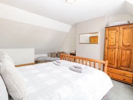 A bedroom with a wooden bed, folded towels, a wooden wardrobe, a chaise lounge with cushions, and a mirror on the wall at Lillies Pad in Methwold near Feltwell