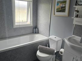 A bathroom with a bathtub and sink at Caban Tywod Abersoch