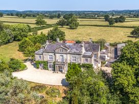 An aerial view of a large house surrounded by fields and trees at Milton Manor in Milton On Stour
