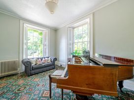 A living room with a sofa and piano at Milton Manor in Milton On Stour
