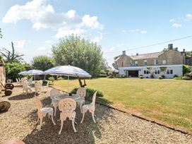 A garden with tables and chairs under umbrellas at Milton Manor in Milton On Stour